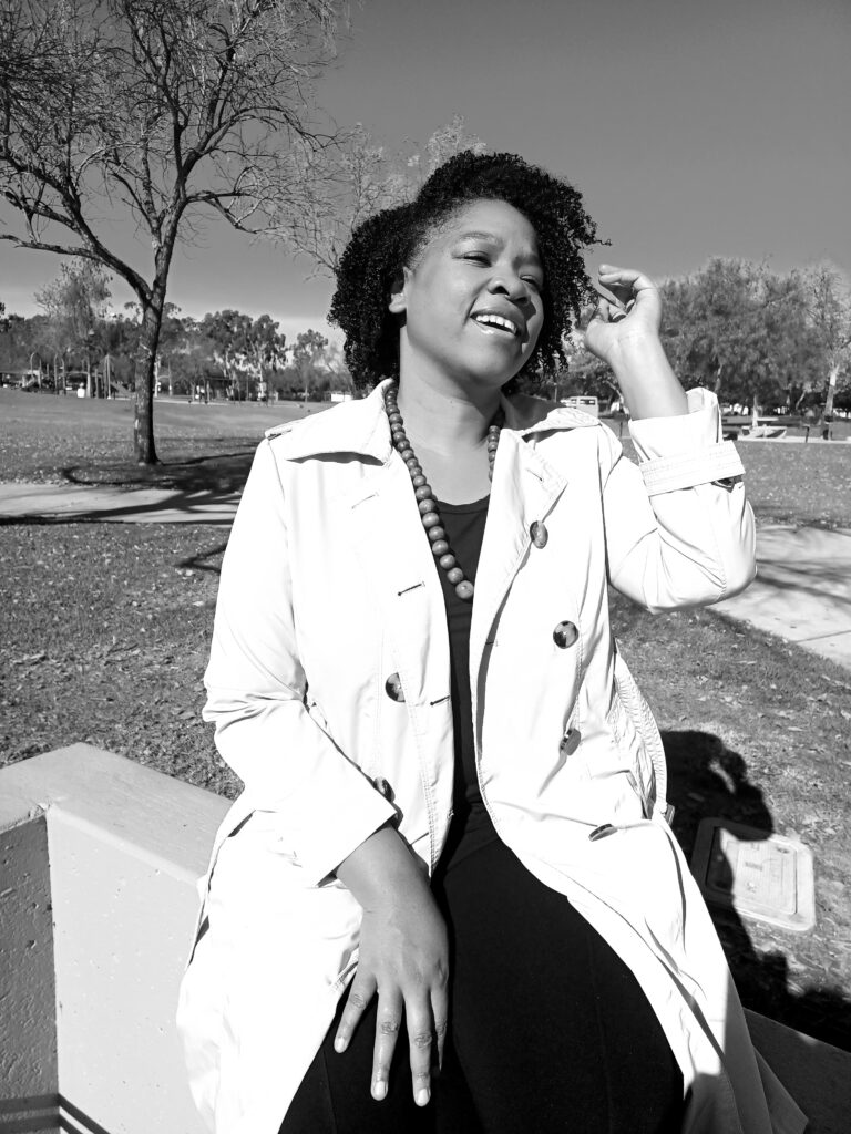 a woman sitting in the park, moving hair from her face. 